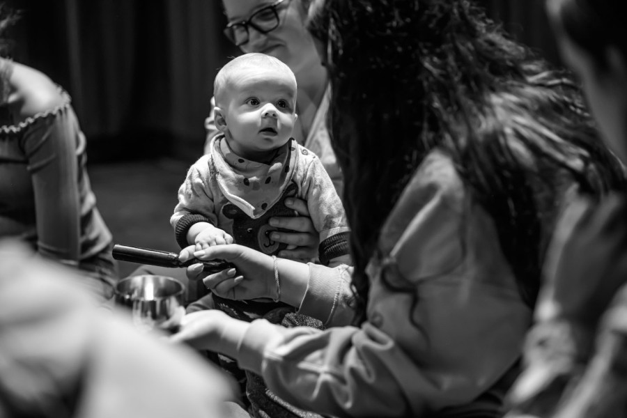 Connect - a baby looks intently at a young performer playing a sound bowl