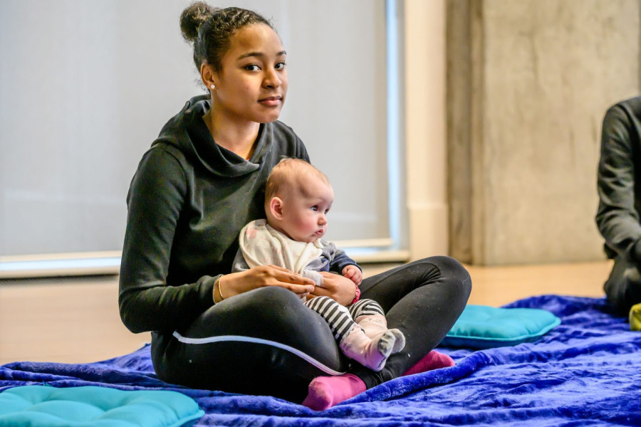 Connect at Lambeth College - a young performer sits with a baby in her lap