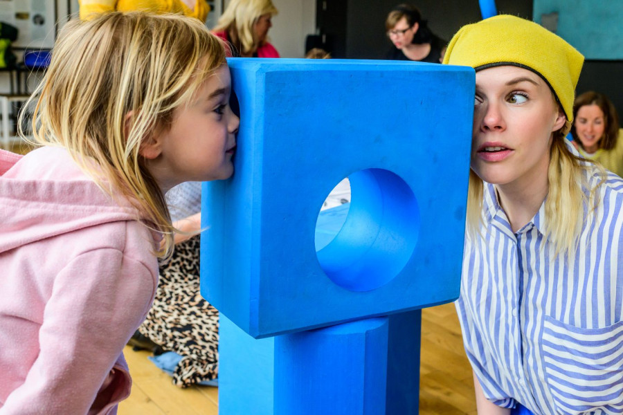 Blue - a performer and a child look at each other through the holes at either side of a blue foam block
